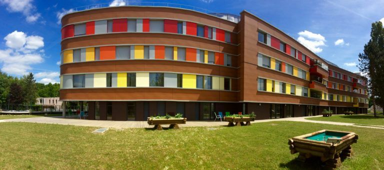 colorful red orange yellow exterior facade of the EHPAD Le Patio with its garden