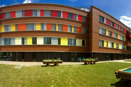 colorful red orange yellow exterior facade of the EHPAD Le Patio with its garden