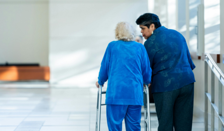 Personne âgées qui est accompagnée par une aide soignante